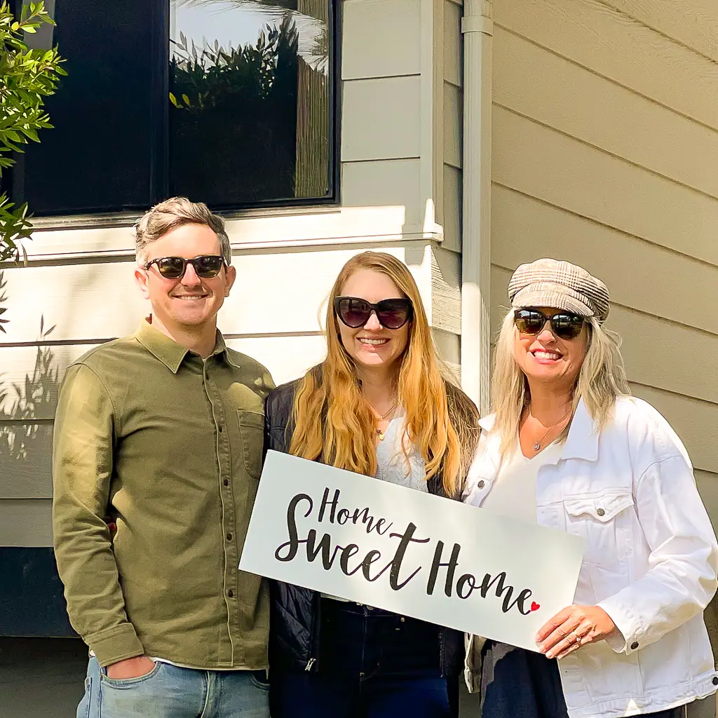 Jennifer Lawson with clients holding a home sweet home sign